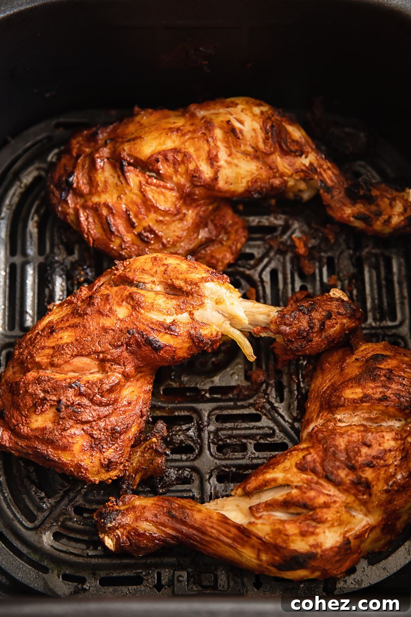 Two pieces of marinated tandoori chicken placed in an air fryer basket, ready for cooking