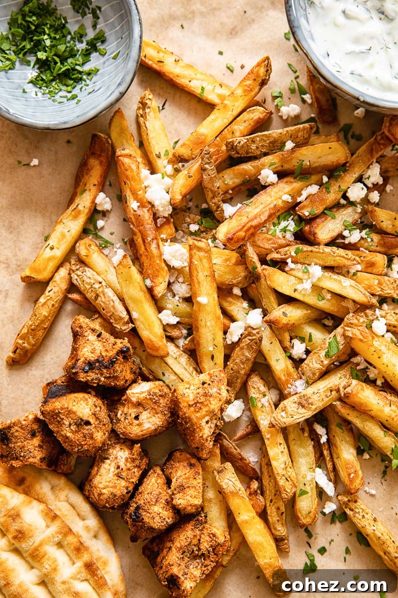 top down view of fries topped with feta, grilled chicken bites, pita and yogourt dip
