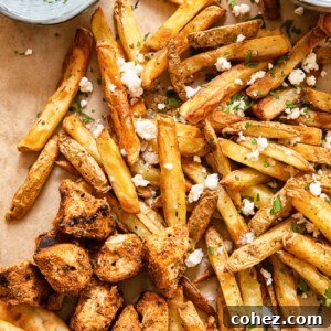 top down view of fries topped with feta, grilled chicken bites, pita and yogourt dip