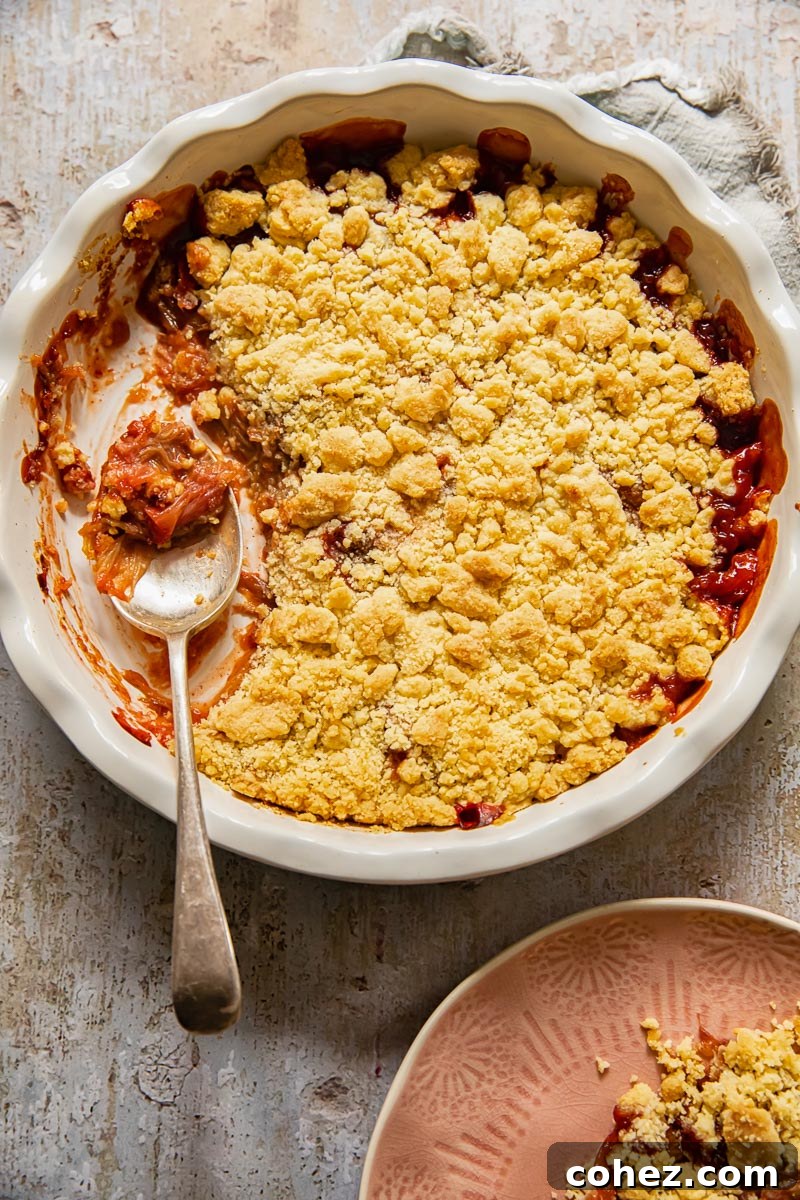 A golden, inviting fruit crumble served in a round pie dish, with a serving spoon ready to scoop.