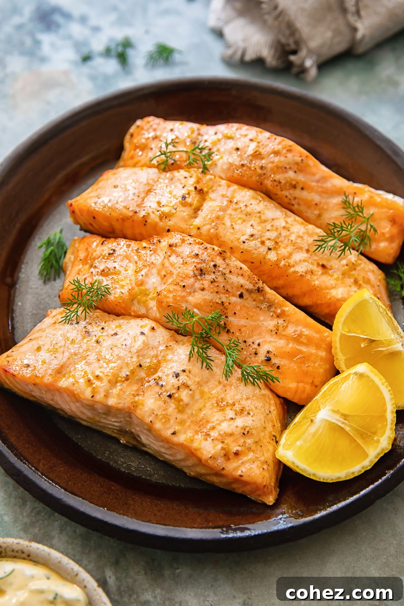 Crispy air fryer salmon fillets garnished with fresh lemon wedges and dill on a white plate