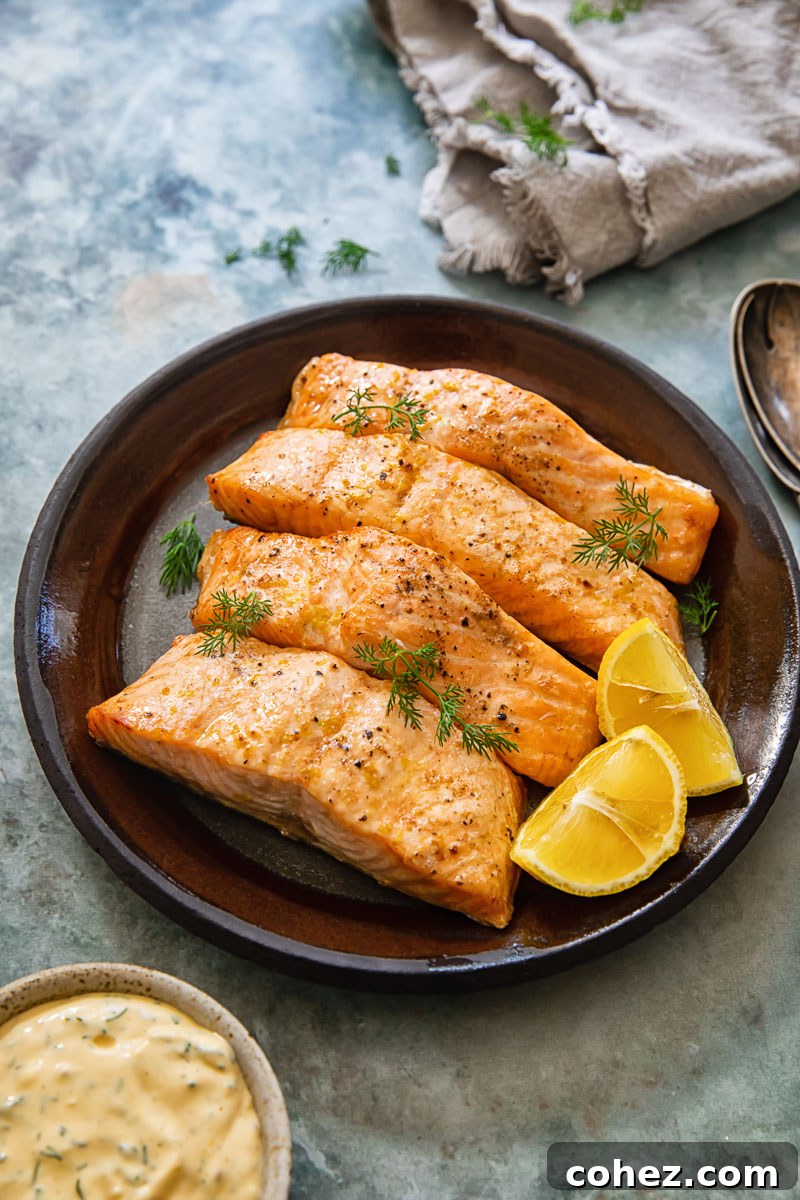 Top-down view of flaky air fryer salmon with a side of creamy lemon dill sauce, accompanied by a napkin