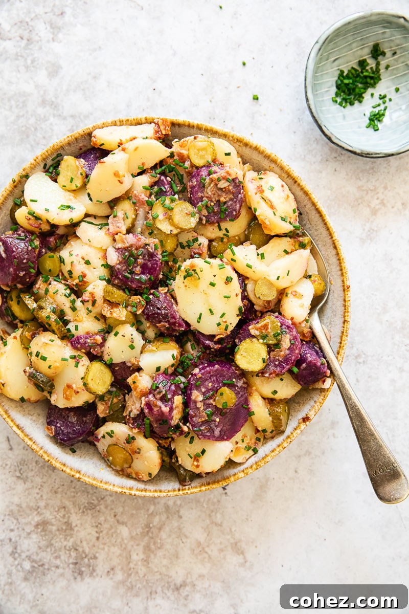 white and purple potato salad in a bowl with a spoon in it