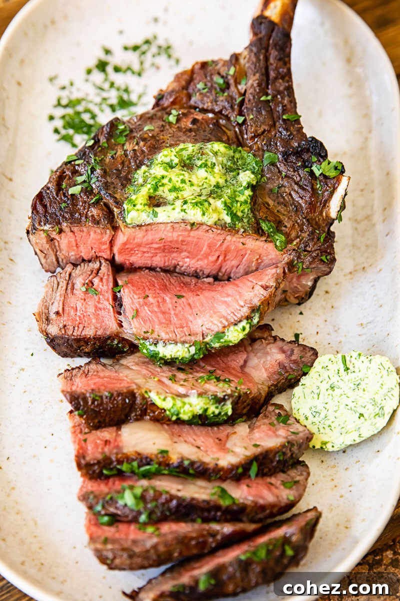 Top-down view of a beautifully grilled and sliced tomahawk steak on a platter, adorned with melted herb butter, ready to be served.