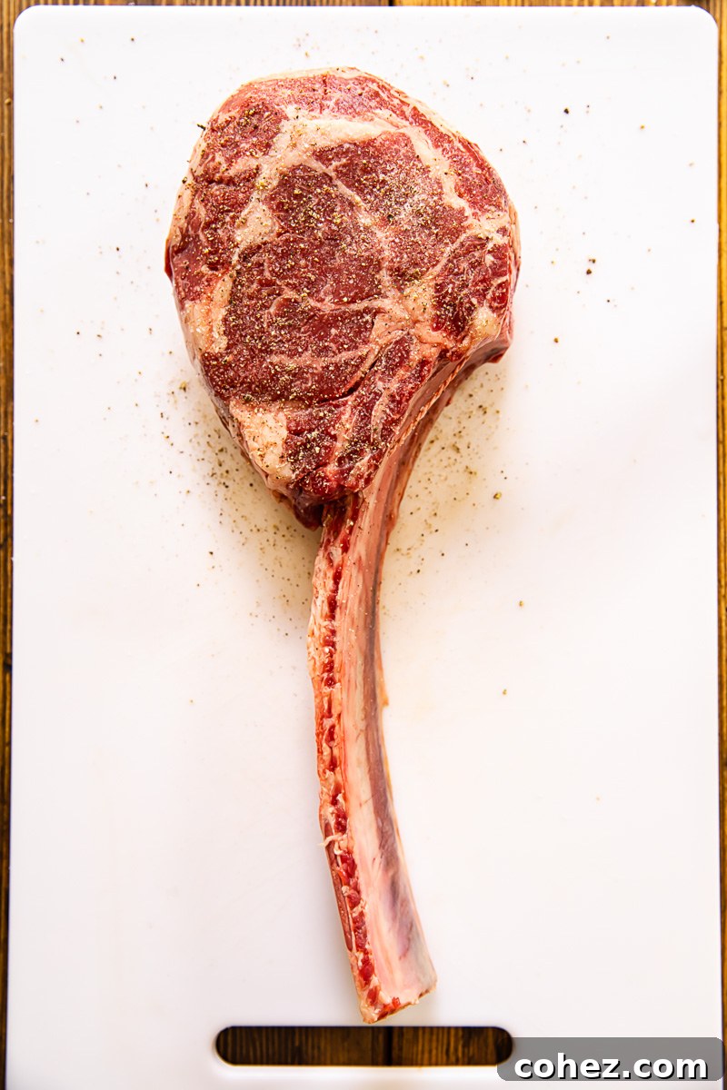 Raw, uncooked tomahawk steak, showcasing its impressive bone and marbling before grilling.