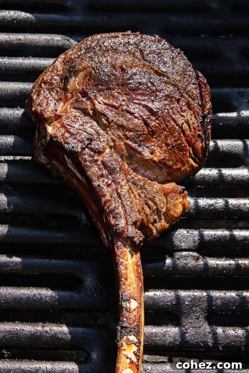 A thick tomahawk steak sizzling on a hot grill, developing a beautiful sear and enticing grill marks.