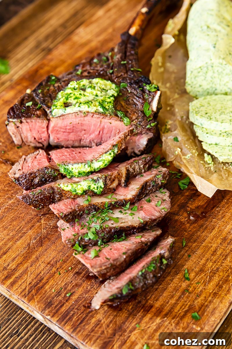 Perfectly cooked and sliced tomahawk steak on a wooden cutting board, topped with herb butter, ready to serve.