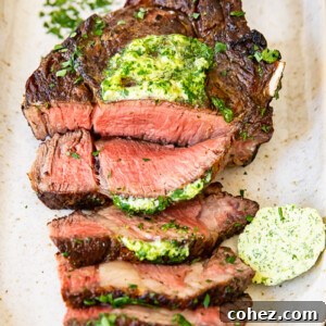 top down view of grilled and sliced steak on a platter, topped with herb butter