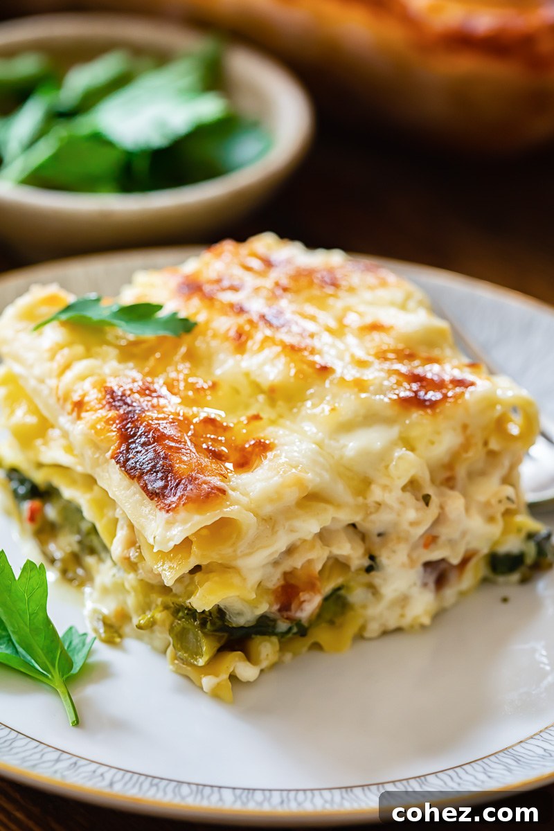 A single perfectly cut slice of white chicken lasagna presented on a white plate, ready to be enjoyed.