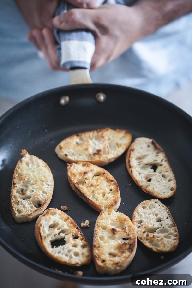 A frying pan filled with slices of bread, perfectly golden and toasted, ready to be topped.
