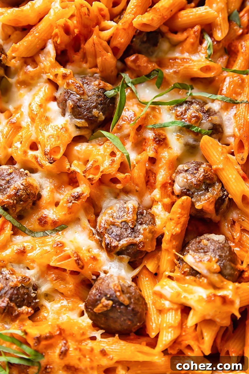 Close up of baked penne alla vodka with meatballs, showcasing the melted cheese and creamy sauce.