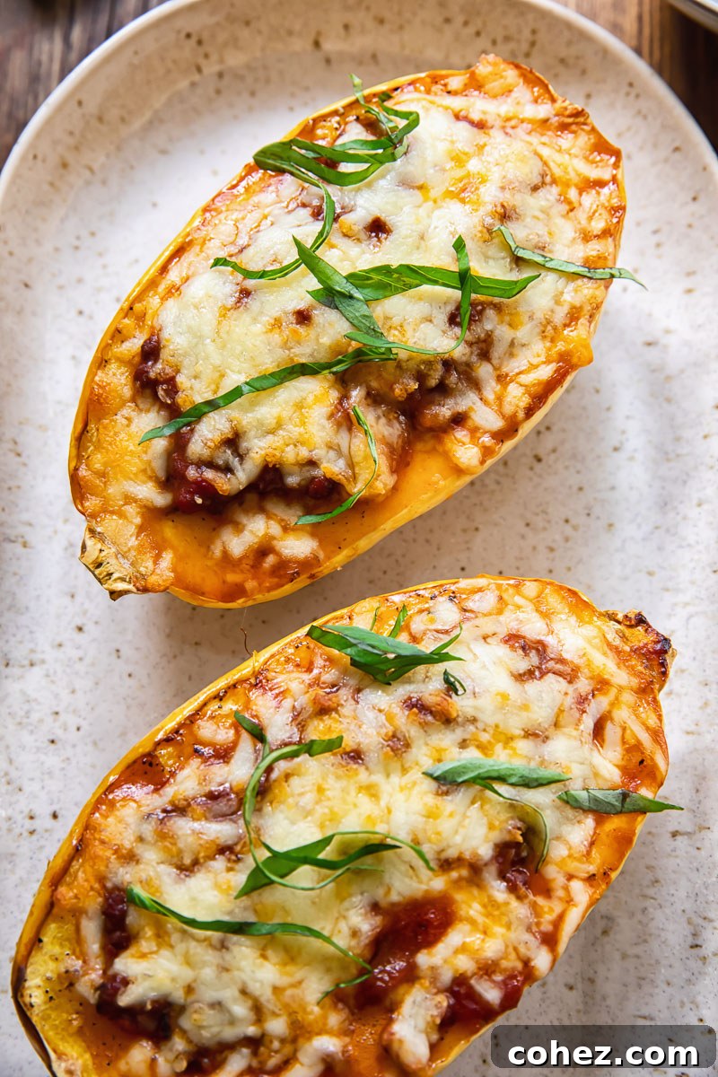 Two halves of stuffed spaghetti squash bolognese, beautifully baked with melted cheese, presented on a serving platter.