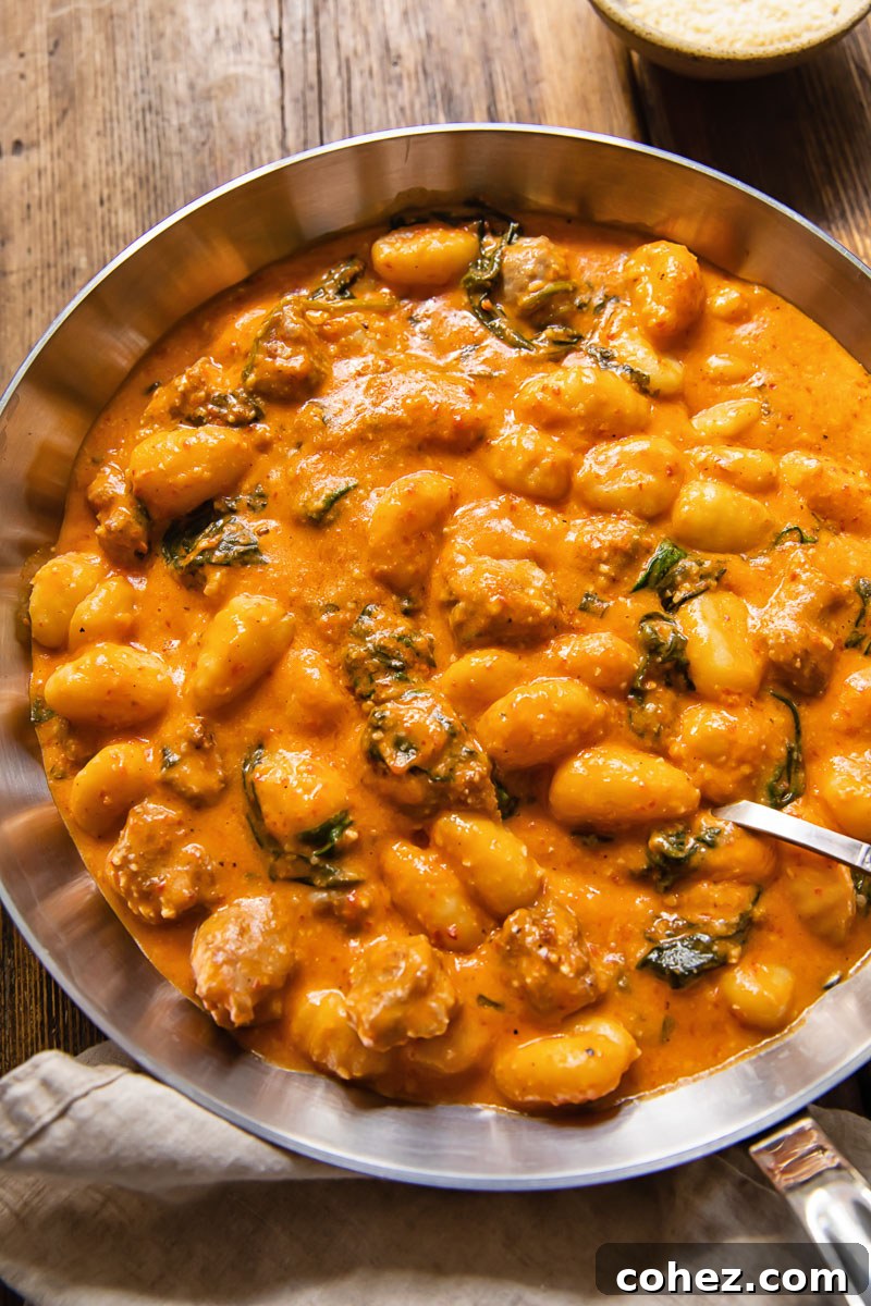 Top-down view of gnocchi with sausage and Romesco sauce in a pan, ready to be served.