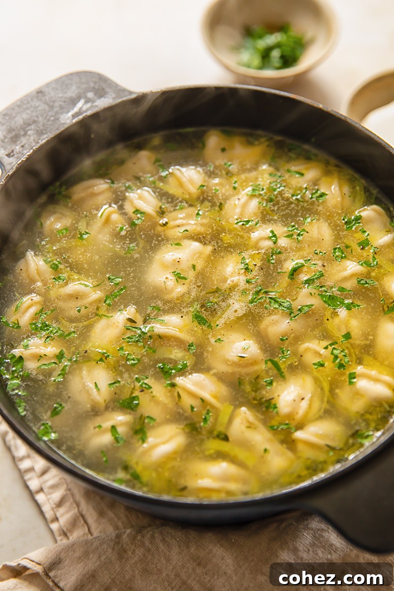 A large pot of simmering Pelmeni Dumpling Soup, filled with vegetables and dumplings, ready to be served.