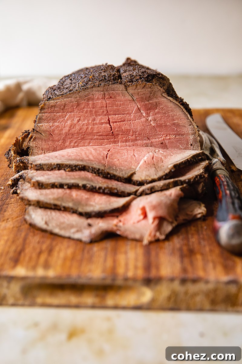 Slices of roast beef and whole beef joint on cutting board, ready to be served.