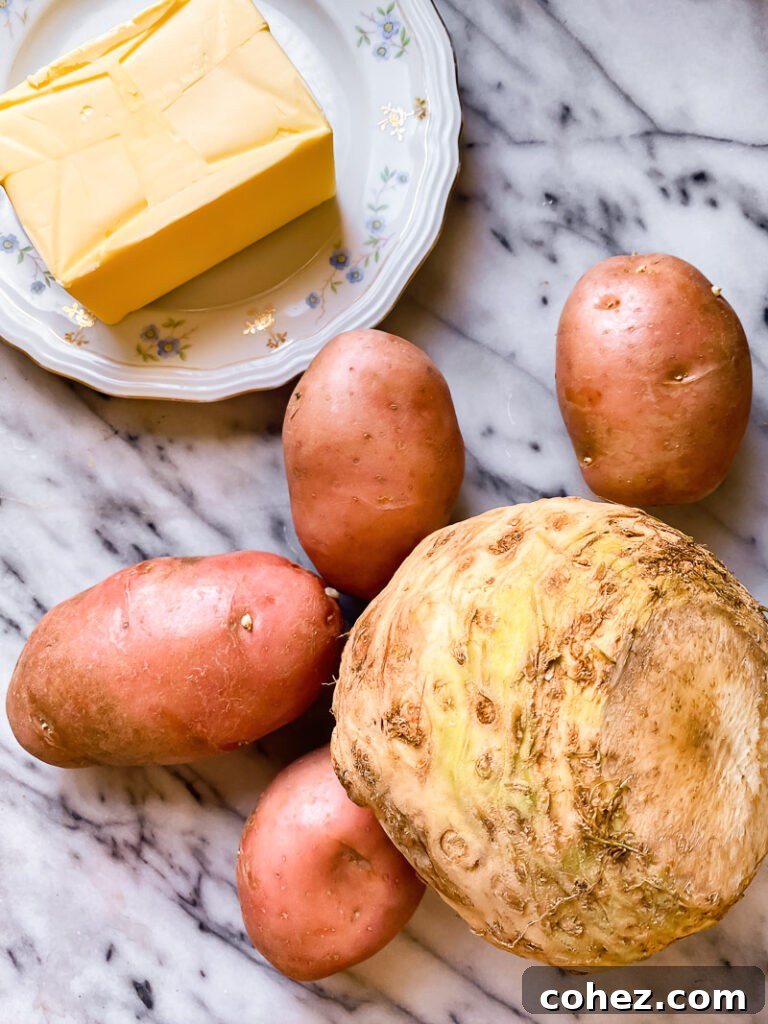 Raw celeriac, starchy potatoes, and a block of butter on a rustic wooden surface, highlighting the key ingredients before cooking.