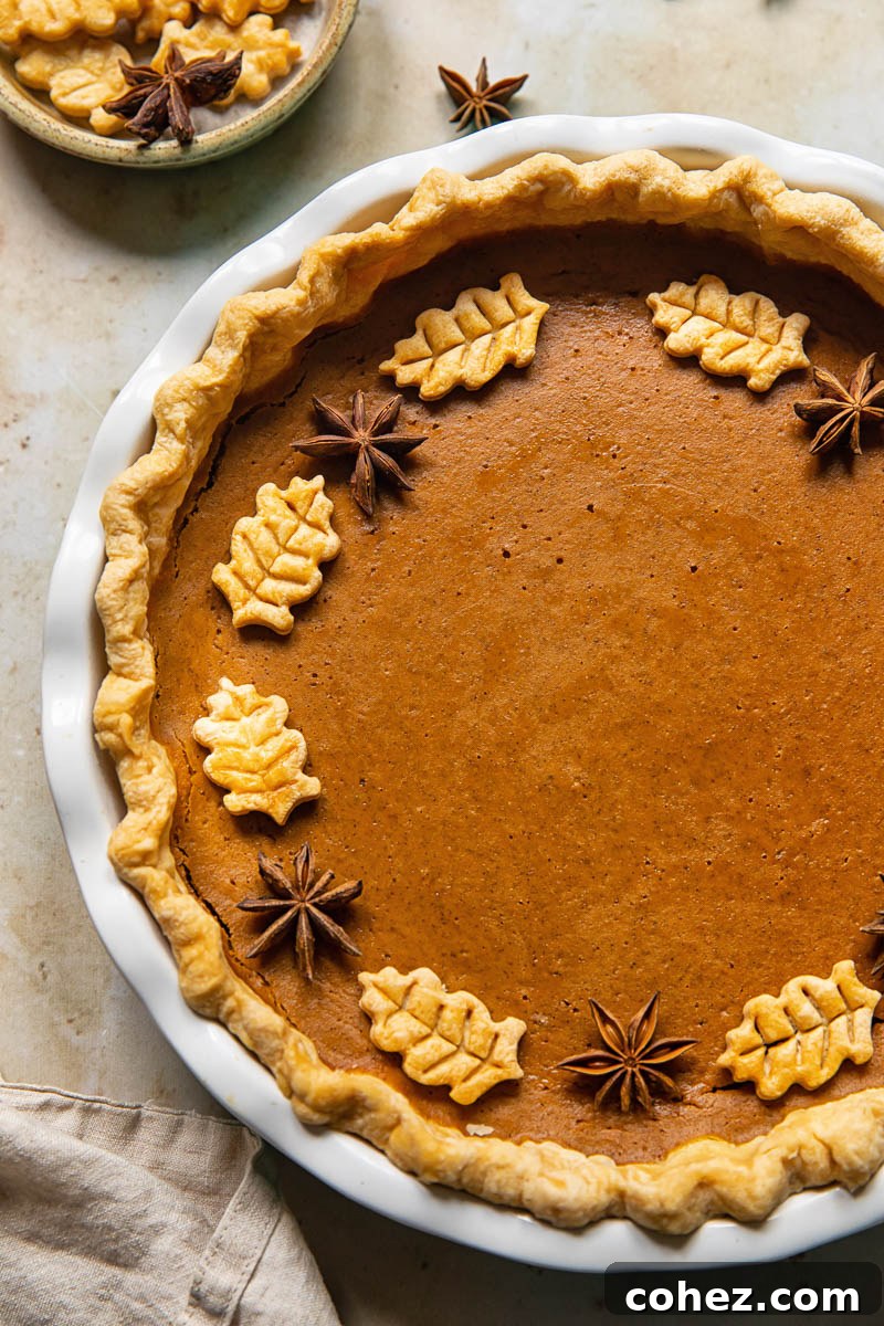 top down view of pumpkin pie decorated with pastry leaves and star anise