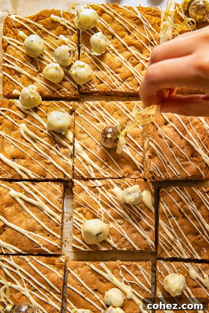 A hand delicately adding a sprinkle of chopped hazelnuts as decoration to a batch of freshly cut hazelnut blondies.