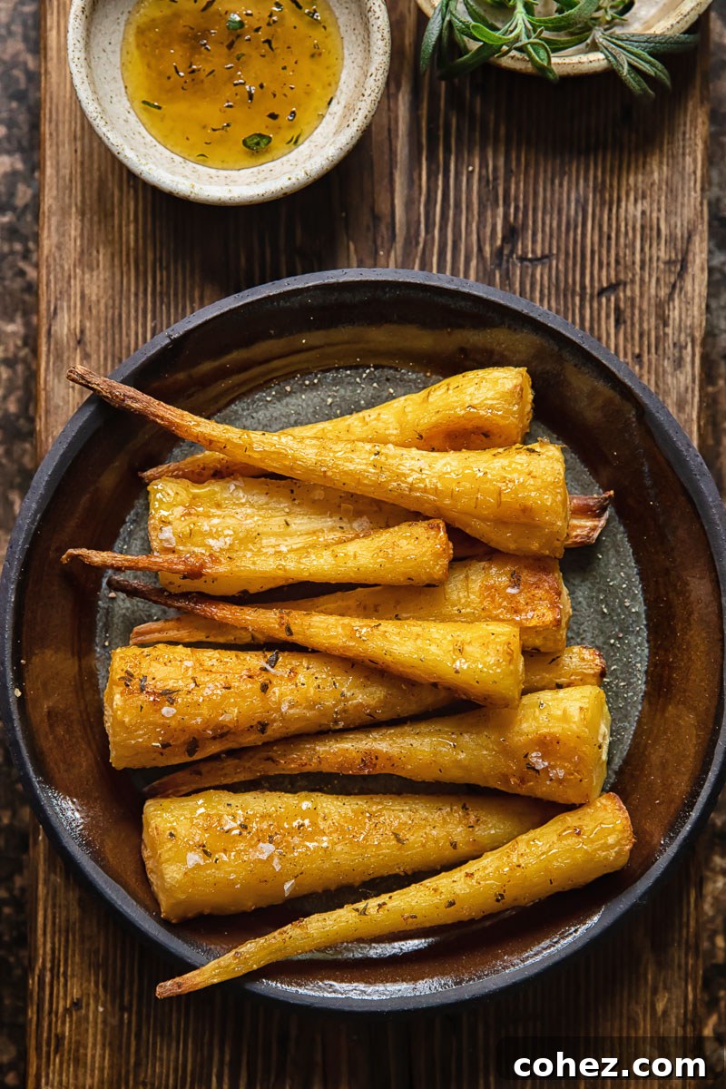 Top-down view of a serving plate filled with honey garlic roasted parsnips on a rustic wooden background.