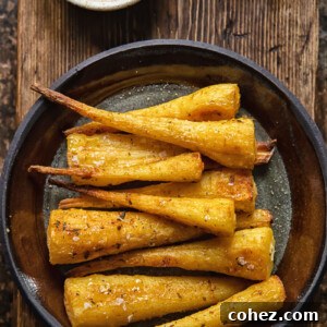 Top-down view of roasted parsnips on a plate on a wooden background, showing the golden glaze.
