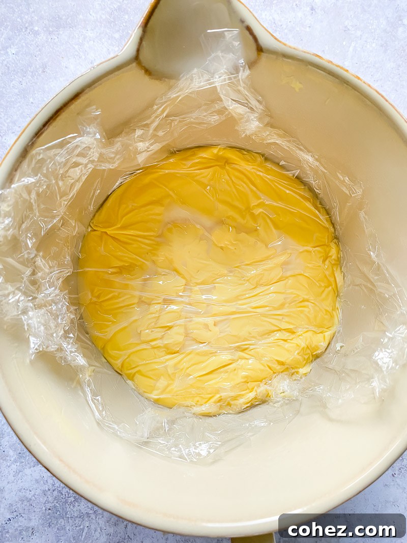 top down view of custard in a bowl with plastic wrap on top