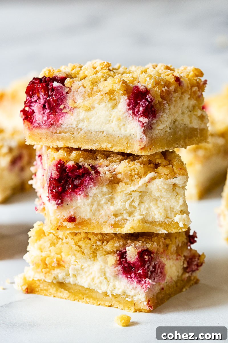 Raspberry Almond Cheesecake Delights 2 Three almond raspberry cheesecake bars stacked on top of each other, showcasing the creamy filling, raspberry swirls, and almond crust.
