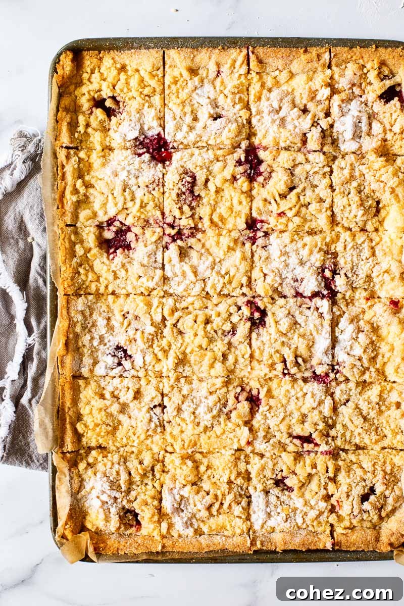 Raspberry Almond Cheesecake Delights 3 An overhead view of a sheet pan filled with perfectly cut almond raspberry cheesecake bars, ready to be served.