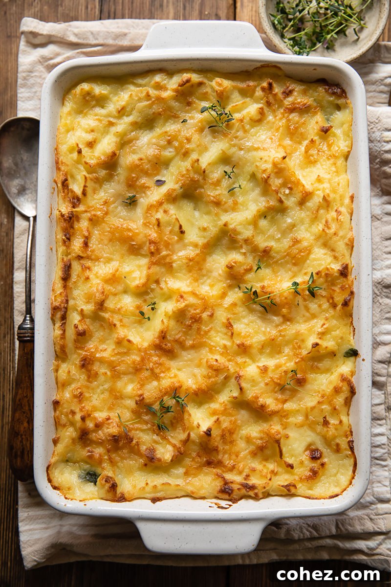 Effortless Fish Pie 3 A close-up top-down view of a golden-baked mashed potato topping on a casserole dish, ready to be filled with creamy fish mixture, showcasing its fluffy texture and golden peaks.