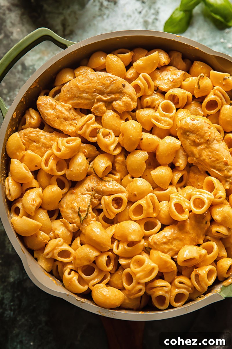 Rich Tomato Cream Pasta with Chicken and Crispy Pancetta 5 top dow view on a pasta dish in a pam on blue background