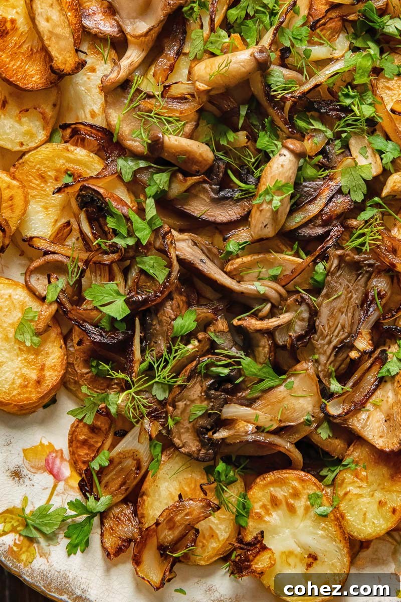 Close-up of crispy fried potatoes topped with sautéed mushrooms, garnished with fresh herbs.