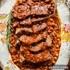 top down view of sliced pot roast with vegetables and chickpeas on a platter