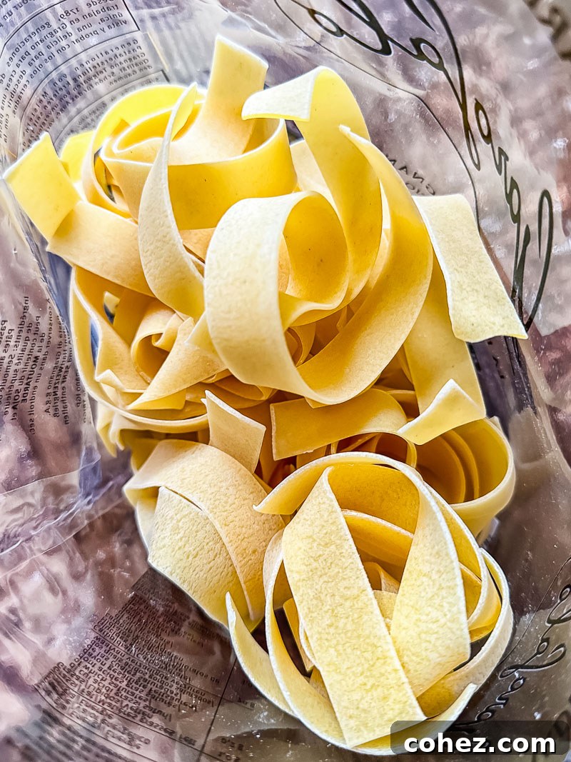 Dried pappardelle pasta, ready for cooking, in a clear plastic bag.