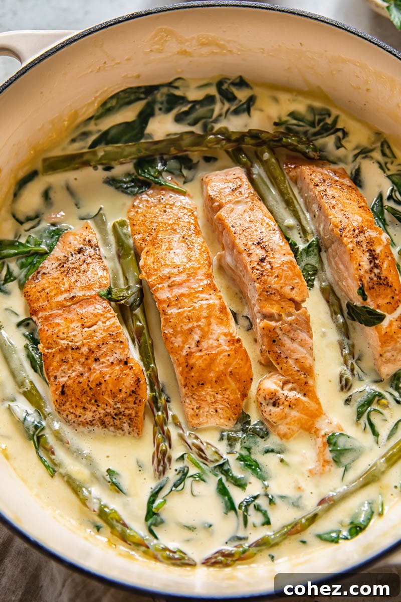 salmon in a pan with creamy sauce and greens