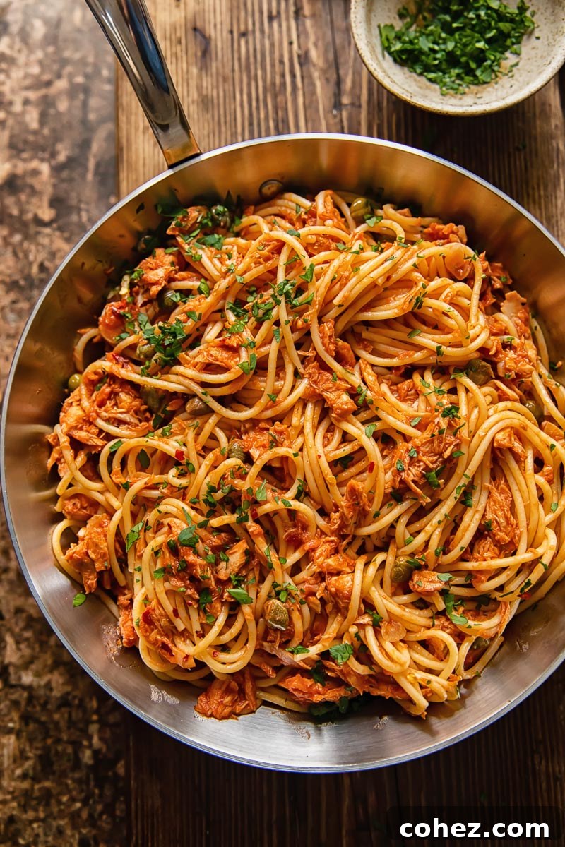 top dow view of tuna pasta in a tomato sauce in a pan on dark wood background