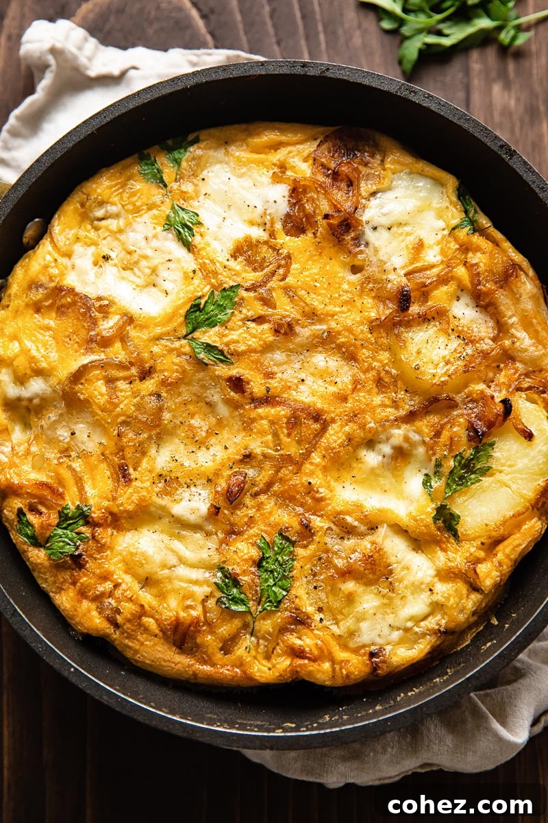A top-down view of a frittata perfectly cooking in a frying pan on the stovetop before heading to the oven.