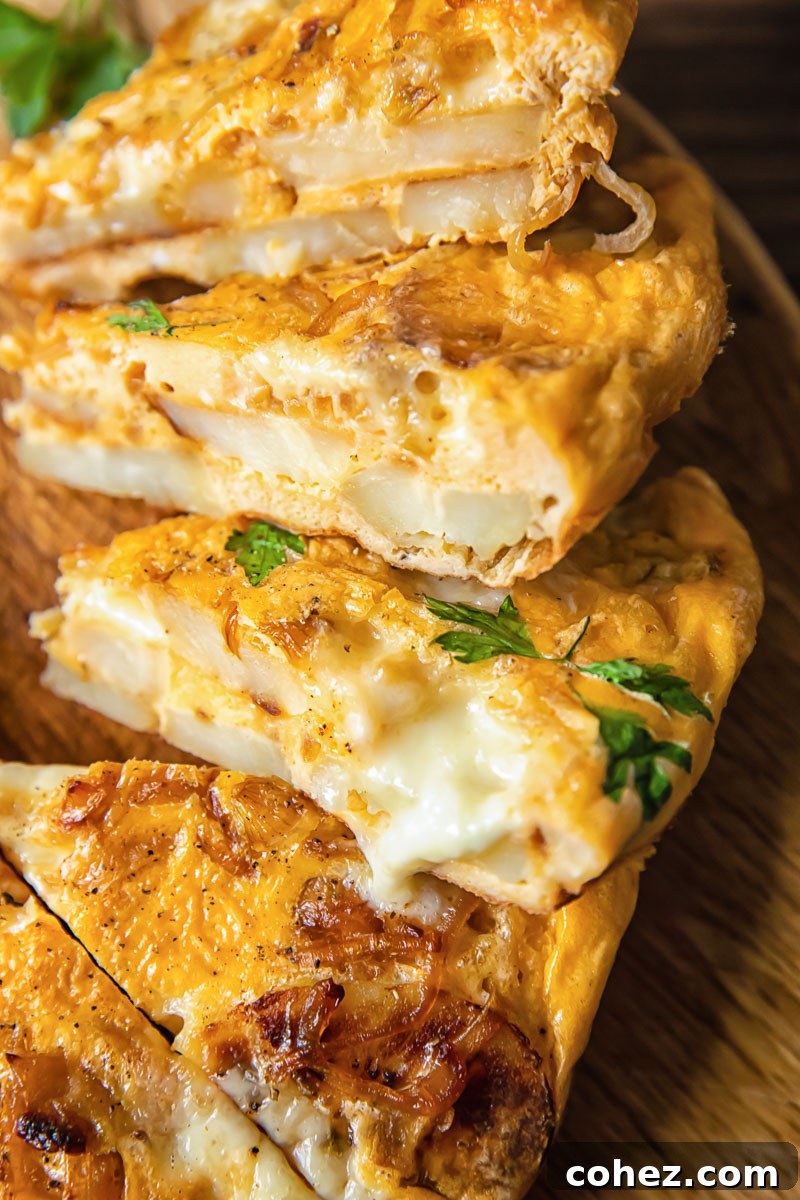A close-up shot of a thick slice of potato frittata with melting Taleggio cheese oozing from the center, highlighting its creamy texture.