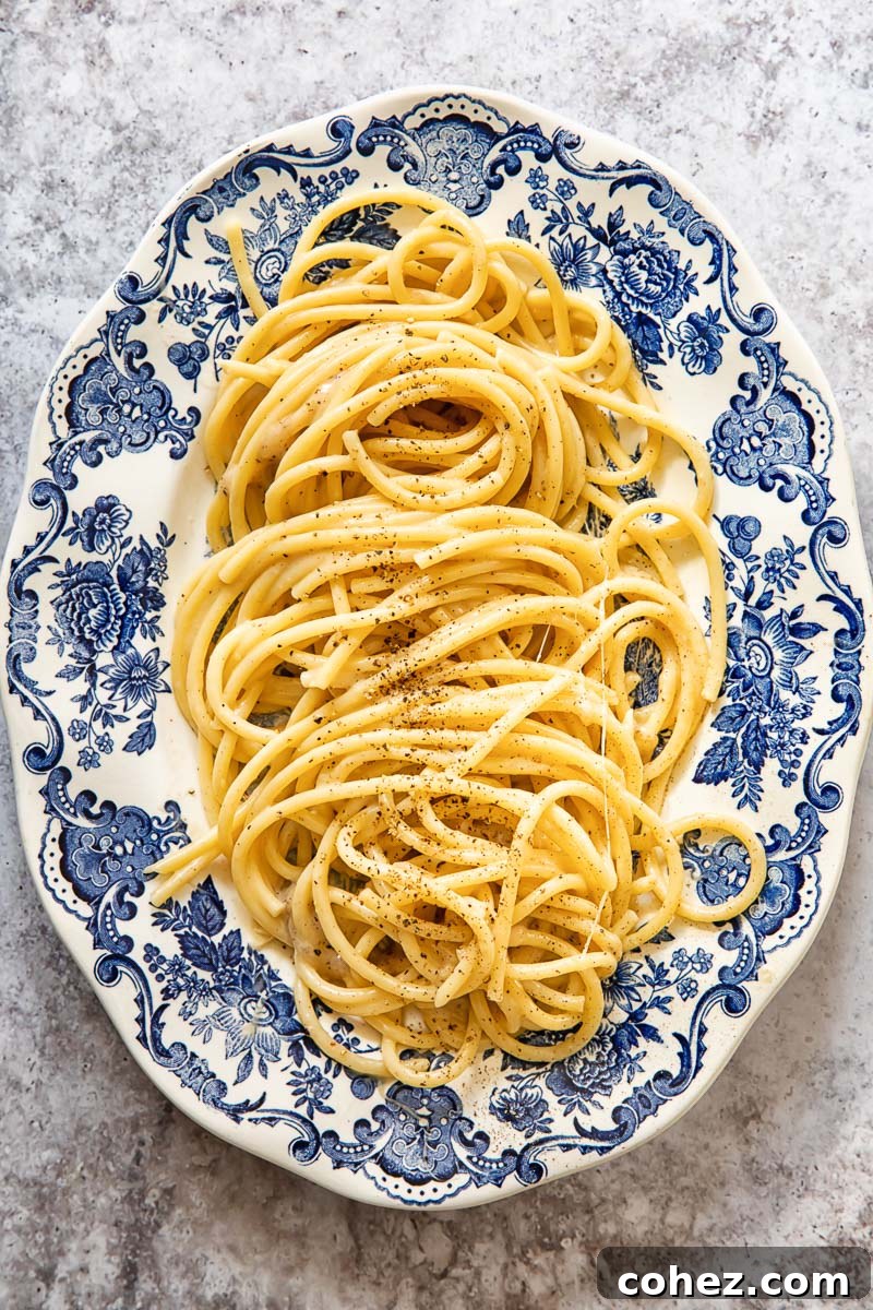 Bucatini Cacio e Pepe served on a beautiful blue and white oval platter, ready to be enjoyed.