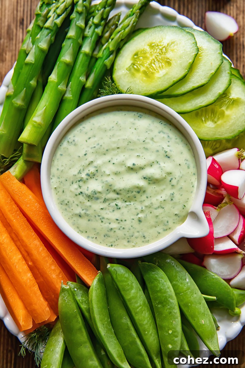 A beautifully arranged platter of fresh vegetables encircling a bowl of vibrant green goddess dip, ready for a healthy and refreshing snack.