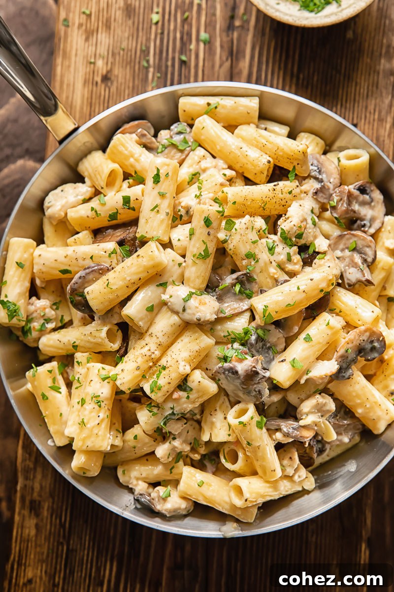 Hearty Italian Sausage and Mushroom Pasta 3 Top-down view of creamy pasta with chicken sausage and mushrooms simmering in a large pan.