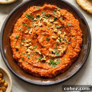 Top down view of Muhammara dip in bowl sprinkled with walnuts and parsley