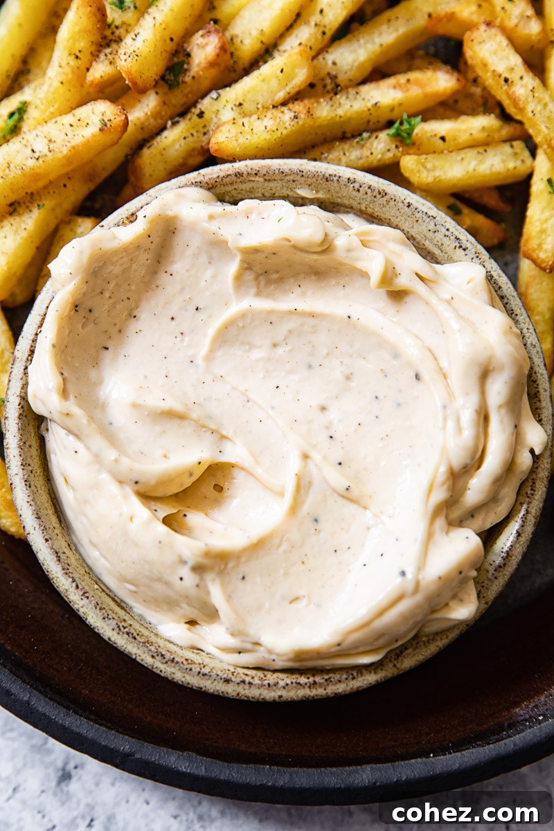 Decadent Truffle Aioli 3 Close up shot of truffle aioli in a bowl next to fries.