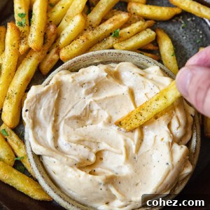 Decadent Truffle Aioli 6 Top down shot of person dipping a fry into truffle aioli dip.