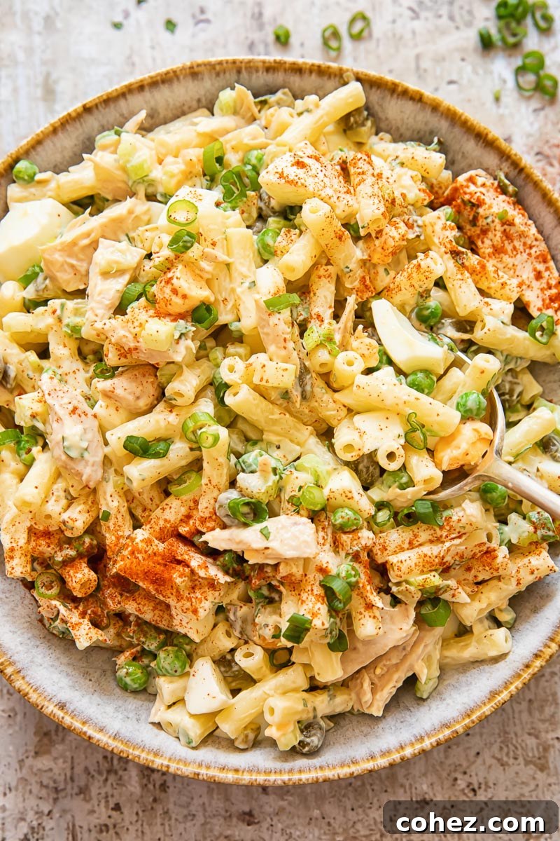 Top down view of tuna macaroni salad in a large bowl, garnished with fresh herbs and showcasing its vibrant colors.
