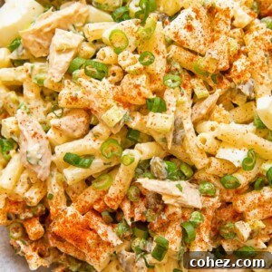Close up of tuna macaroni salad with peas and green onion in a bowl.