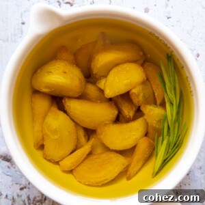 top down view of confit garlic cloves in oil in a white cup