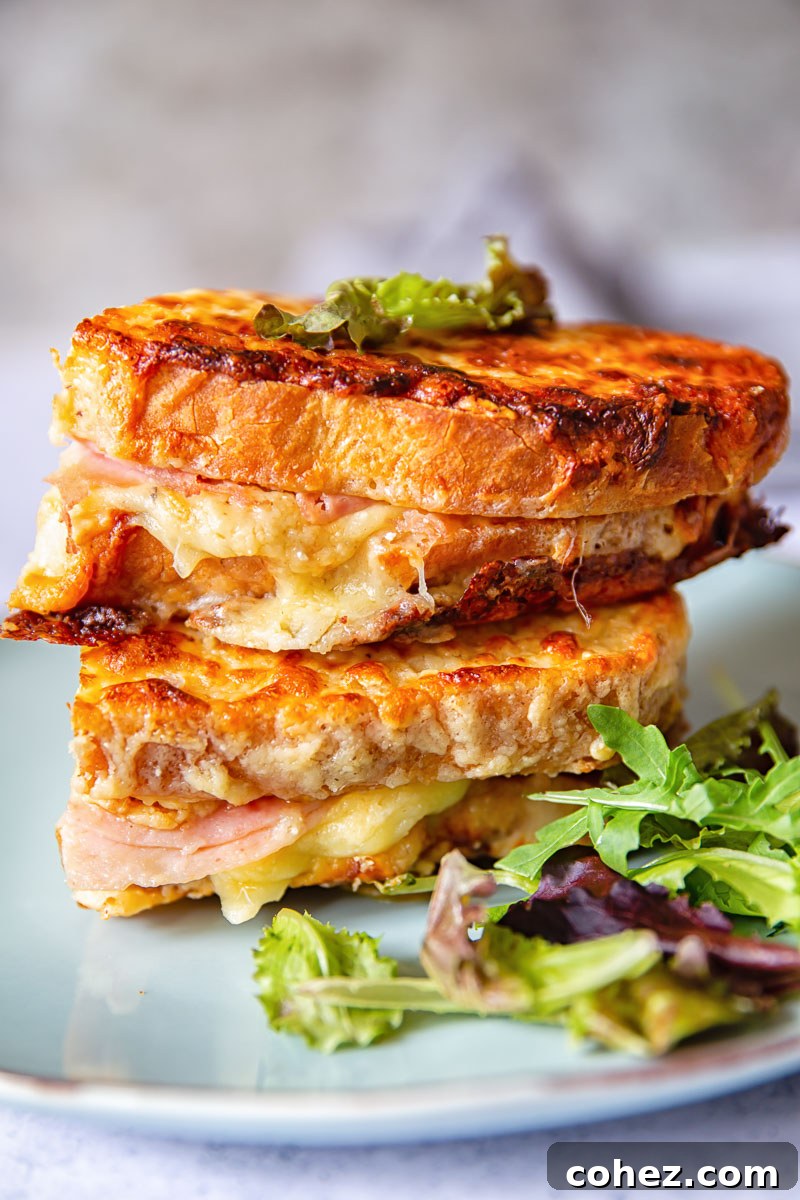 Two golden Croque Monsieur sandwiches piled high on a plate with fresh lettuce leaves