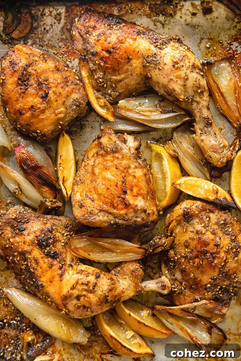 Top down view of za'atar chicken cooked with lemon and garlic on a baking tray, ready to be served.