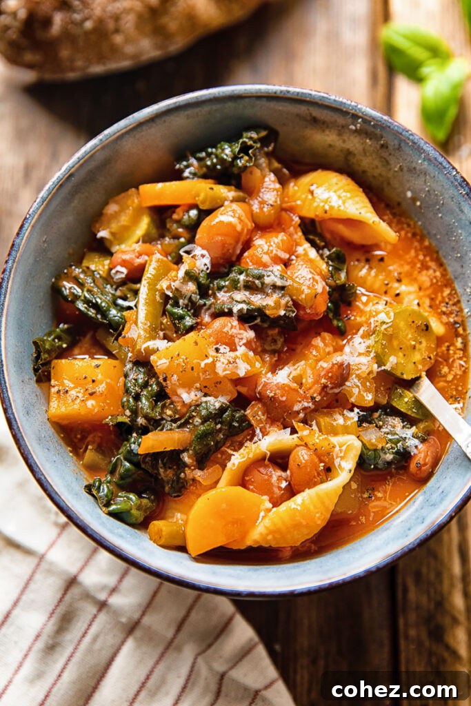 Bowl of minestrone soup with a spoon, garnished with fresh herbs and a drizzle of olive oil.