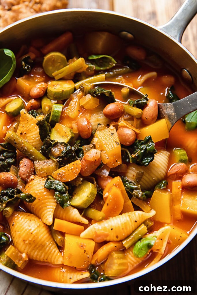 A large pot of minestrone soup simmering on the stove, with a ladle resting inside, showcasing its rich, thick texture.