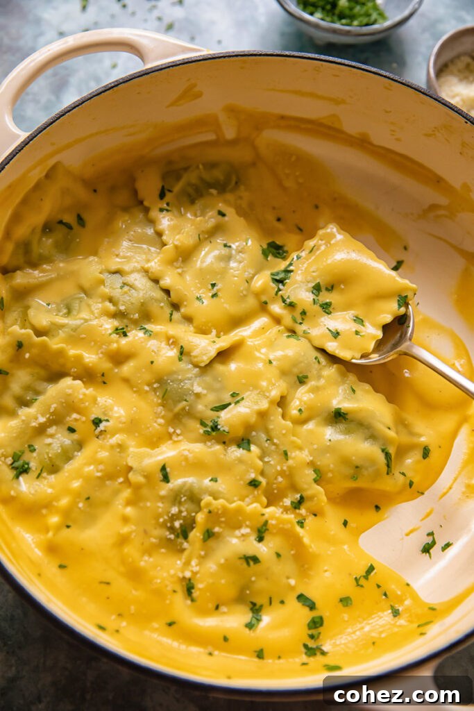 spoon holding a parcel of ravioli in pot of pasta in squash sauce